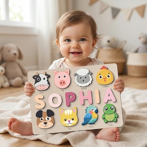 Puede incluir: Rompecabezas de animales de madera con el nombre "SOPHIA" en letras rosas y rosa claro. El rompecabezas presenta formas de animales coloridas, incluyendo una vaca, cerdo, oveja, pollo, perro, gato, loro y tortuga. El niño sostiene el rompecabezas.