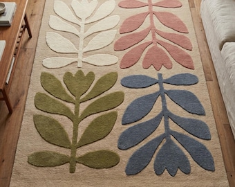 May include: A rectangular area rug with a beige background and four large floral designs in white, pink, green, and blue. The rug is made of a soft, textured material and is placed on a wooden floor.