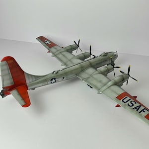 Pu&ograve; includere: Modello dettagliato di un bombardiere B-29 Superfortress. Il modello &egrave; dipinto in tonalit&agrave; di grigio con accenti rossi e bianchi sulla coda e sulle ali. Le ali presentano la scritta "USAF" in blu. Ha quattro eliche.