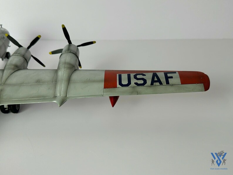 Pu&ograve; includere: Un modello dettagliato di aereo con ali argentate e coda con punta rossa. Il modello presenta quattro eliche con pale nere e punte gialle. Il testo "USAF" &egrave; stampato sull'ala.