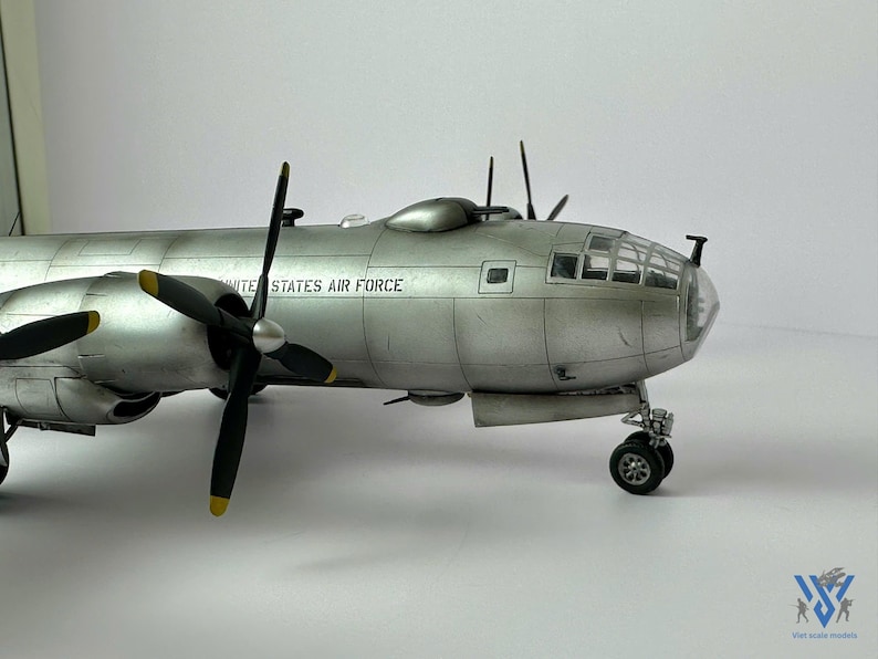 Pu&ograve; includere: Modello dettagliato di un bombardiere d'argento della United States Air Force. Il modello presenta quattro eliche nere con punte gialle, un abitacolo trasparente e la scritta "UNITED STATES AIR FORCE" sul lato. Il carrello di atterraggio &egrave; visibile.