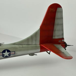 Pu&ograve; includere: Modello dettagliato di una sezione di coda di aereo, con schema di colori rosso e argento. La deriva ha il numero "7151" stampato sopra. Un emblema a stella blu e bianco &egrave; visibile sulla fusoliera. Il modello &egrave; ambientato su uno sfondo semplice.