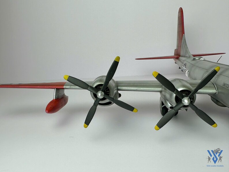 Pu&ograve; includere: Modello dettagliato di aereo con fusoliera argentata, dettagli rossi e gialli sulle ali e sulla coda, e quattro eliche nere con punte gialle. Il modello ha un design dettagliato ed &egrave; ambientato su sfondo bianco.