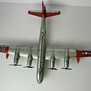 Pu&ograve; includere: Vista dall'alto di un modello di aereo con fusoliera argentata ed estremit&agrave; alari rosse. Le ali hanno quattro motori ed eliche. La coda presenta "USAF" e un'emblema a stella. Replica dettagliata di un aereo d'epoca.