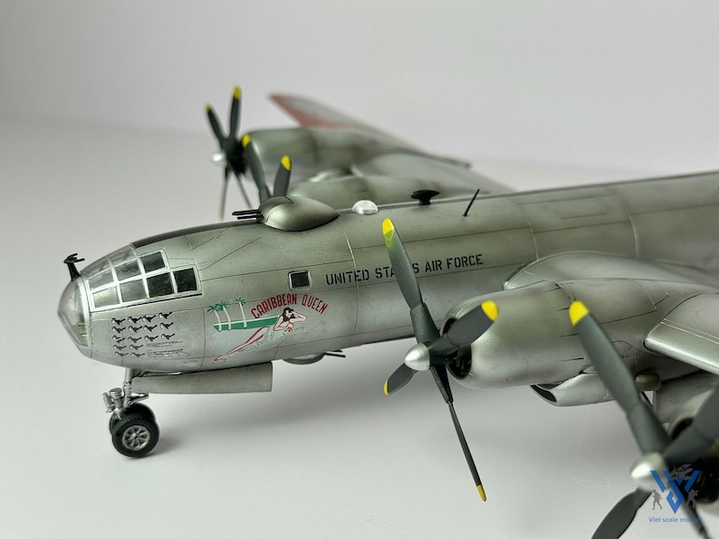 Pu&ograve; includere: Modello dettagliato di un bombardiere d'argento dell'aeronautica militare statunitense. Il modello presenta quattro eliche con punte gialle, un abitacolo dettagliato e la scritta "Caribbean Queen" con un'illustrazione.