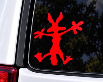 May include: A bright red vinyl decal sticker featuring a stylized, abstract silhouette of a cartoon coyote character in a flattened, splayed-out pose. The design is applied to the dark glass surface of a vehicle window, showing sharp edges.