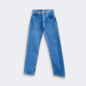 May include: A pair of high-waisted blue denim jeans featuring a classic straight-leg cut, a button-fly closure, five pockets, and a medium wash finish with subtle fading along the thighs and seams, presented in a clean, flat-lay orientation.