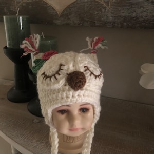 May include: White crocheted owl hat with brown felt eyes and nose, pink and green yarn accents, and long ties.