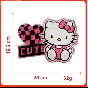 May include: A set of three embroidered patches featuring a Hello Kitty design, a pink and black checkered heart, and the word "CUTE". The patches are approximately 19.2 cm tall and 26 cm wide.