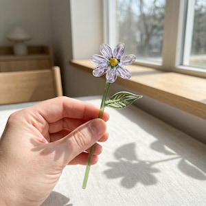 May include: A white ceramic mug with a black handle and the text "But First, Coffee" in a bold, black font. The mug is set against a neutral background, highlighting its simple design.