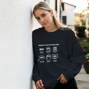 Peut inclure: Sweat-shirt noir avec texte et graphiques blancs. Le texte dit "THINGS I DO IN MY SPARE TIME" au-dessus de six illustrations d'activités liées aux camions de pompiers. Les activités incluent la conduite, parler de, la recherche, rêver de, penser à et regarder les camions de pompiers.