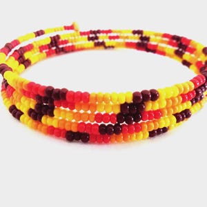 May include: A multi-strand wrap bracelet constructed from small, round beads in a repeating pattern of bright yellow, vibrant orange, deep red, and dark maroon colors, arranged in a continuous spiral design that circles multiple times.