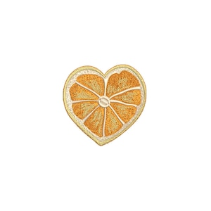 Könnte beinhalten: Gestickter Aufnäher in Herzform, der einen Querschnitt einer Orange darstellt. Der Aufnäher hat einen goldenen Rand, und die Orangensegmente sind in Orange- und Gelbtönen gehalten.