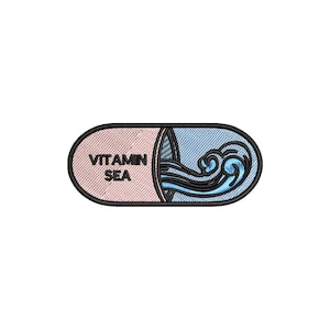May include: Embroidered patch in the shape of a capsule, with the words "VITAMIN SEA" in black. The capsule is divided into two sections: one pink, the other blue with a stylized wave design.