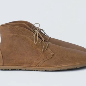 May include: A pair of brown leather ankle boots with laces. The boots have a rounded toe and a flat sole.