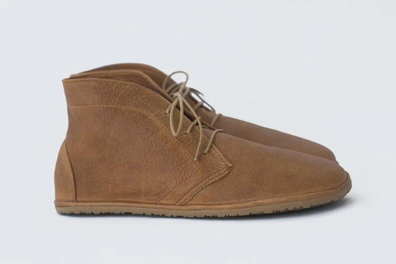 May include: A pair of brown leather ankle boots with laces. The boots have a rounded toe and a flat sole.