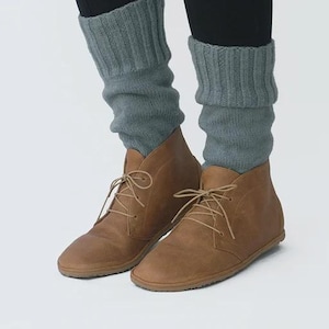 May include: A pair of brown leather ankle boots with laces. The boots are worn with gray knitted leg warmers.