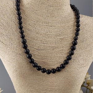 May include: Black gemstone necklace and earrings set. The necklace is made of round black beads and the earrings are dangle style with black beads.