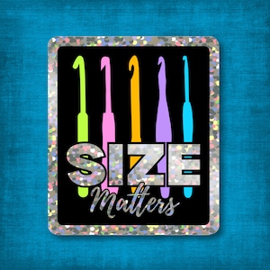 Può includere: Un rettangolo nero con un bordo glitterato argentato presenta il testo "SIZE Matters" in argento e bianco. Cinque uncinetti colorati in verde, rosa, giallo, viola e blu sono disposti verticalmente sopra il testo.