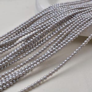 May include: Multiple strands of small, round, grey pearls. The pearls are strung together, forming several lines of beads. The pearls have a lustrous sheen and are arranged in a cascading pattern, suitable for jewellery making.
