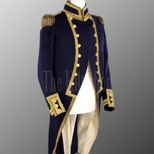 Pode incluir: Um casaco azul marinho de estilo militar com acabamentos e botões dourados. O casaco apresenta ombreiras nos ombros e detalhes dourados ao redor dos punhos e da gola. O casaco é exibido em um manequim.