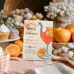 May include: A bridal shower invitation with a watercolor illustration of a cocktail with orange slices. The invitation includes the text "Bridal Shower" and details for Madison Williams' shower on June 19th.
