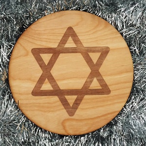 May include: A round wooden plaque with a brown Star of David design. The plaque is surrounded by silver tinsel.
