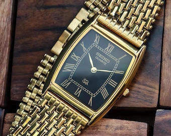 Reloj Seiko vintage de cuarzo dorado con esfera negra y números romanos, único.