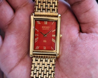Reloj vintage Seiko Slim Tank de cuarzo con esfera roja con números romanos y baño de oro.