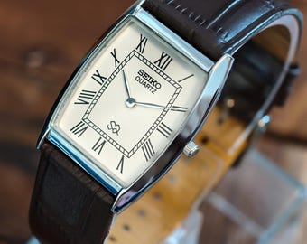 Reloj Seiko Slim de cuarzo vintage con esfera romana blanca y correa de piel negra. Reloj de vestir retro.