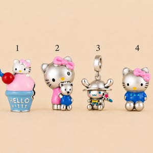 Puede incluir: Cuatro dijes de metal plateado con personajes de Hello Kitty. El dije 1 es un cono de helado rosa y azul con Hello Kitty. El dije 2 muestra a Hello Kitty con un osito de peluche. El dije 3 es un personaje con sombrero y varita mágica.