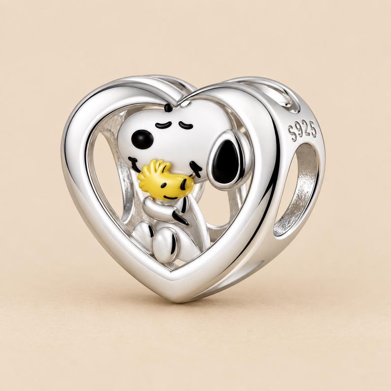 May include: A silver heart-shaped charm featuring a white dog character with black ears and eyes, holding a small yellow bird. The charm has a polished metallic finish and the engraving S925 is clearly visible on the side of the heart frame.
