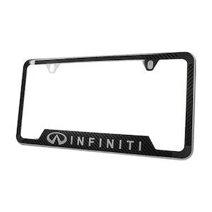 May include: A black license plate frame with a carbon fiber pattern. The word "INFINITI" is displayed in silver lettering at the bottom. The frame has a rectangular shape with rounded corners and mounting holes.