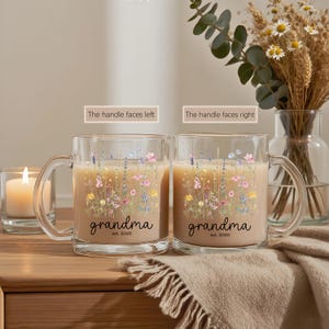 Puede incluir: Dos tazas de vidrio transparente llenas de una bebida de color claro. Cada taza presenta un dise&ntilde;o floral con la palabra "grandma" y el a&ntilde;o "est. 2025". Las tazas est&aacute;n sobre una superficie de madera con una vela encendida y un jarr&oacute;n de flores.