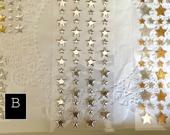 May include: Four sheets of adhesive gold and silver star stickers. The stickers are arranged in rows and columns on a white background. The stickers are perfect for adding a touch of sparkle to any craft project.
