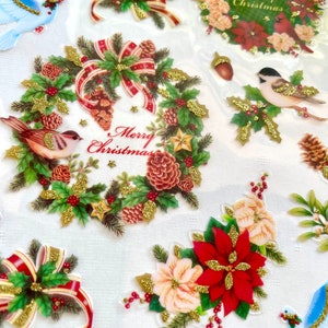 May include: A sheet of Christmas-themed stickers with gold glitter accents. The stickers feature wreaths, poinsettias, birds, and doves. The wreaths have red and green accents and the text "Merry Christmas".