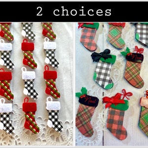 May include: Two choices of Christmas stocking ornaments. The first choice is a set of 12 black and white buffalo plaid stockings. The second choice is a set of 8 red and green plaid stockings with the words "Noel" and "Joy" on two of the stockings.