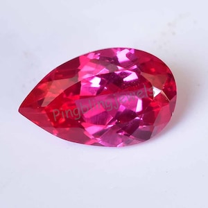 Puede incluir: Una gema facetada en forma de pera, en tonos rojos y rosas. La gema tiene un alto grado de claridad, con múltiples facetas que reflejan la luz. El texto "Pingbling jewels" es visible.
