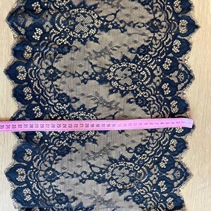 Peut inclure: Tissu en dentelle bleu marine avec un motif floral et des bords festonn&eacute;s. Un ruban &agrave; mesurer rose indique la longueur du tissu. Le tissu mesure environ 89 cm de long.