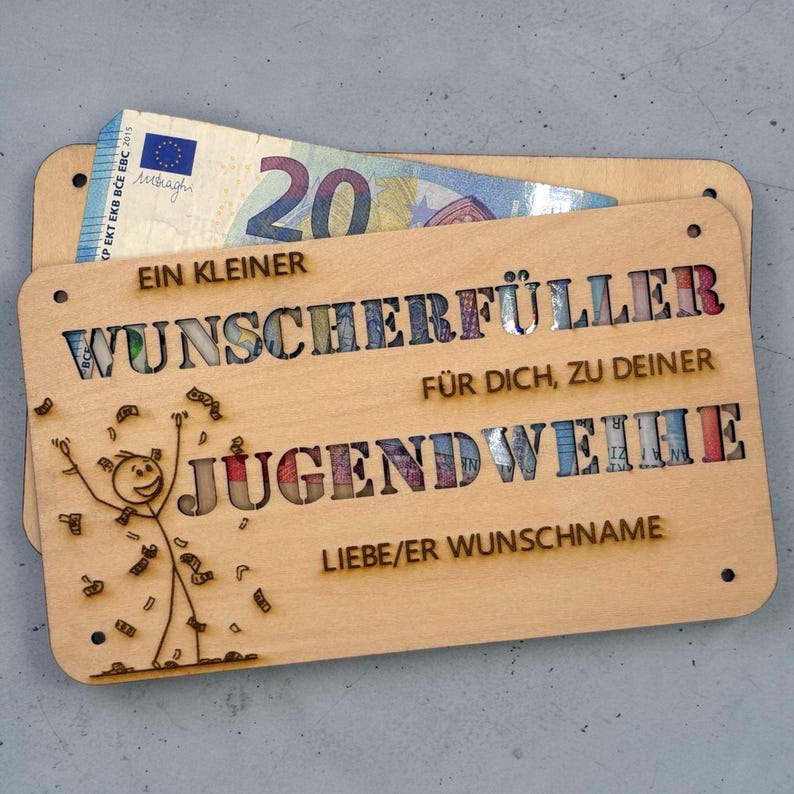 May include: A wooden gift card holder with the words "EIN KLEINER WUNSCHERF&Uuml;LLER F&Uuml;R DICH, ZU DEINER JUGENDWEIHE" cut out. A twenty Euro bill is visible. A stick figure is drawn on the holder.