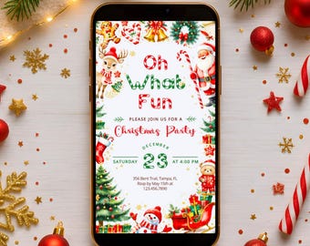May include: A smartphone displays a Christmas party invitation with festive graphics. The invitation reads "Oh What Fun" and "Christmas Party" with a date of December 23rd. The phone is surrounded by Christmas ornaments and greenery.