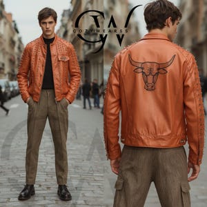 Puede incluir: Chaqueta de cuero color óxido con tachuelas plateadas en hombros y mangas. La chaqueta presenta un gráfico de toro negro en la espalda. El modelo lleva pantalones marrones y zapatos negros. La marca "COZYWEARSS" es visible.