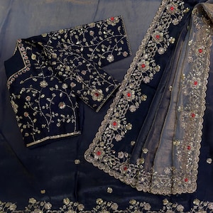 May include: A dark navy blue blouse and matching sheer fabric featuring intricate gold embroidery, silver sequins, and small red circular accents. The blouse has long sleeves and a floral pattern, while the sheer fabric has a wide, ornate border.