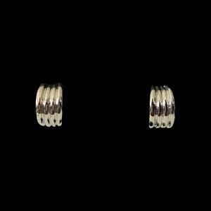 May include: A pair of silver-toned hoop earrings featuring a multi-ribbed, layered design with a polished, reflective finish. Each earring consists of four distinct, parallel curved bands that create a dimensional, stacked appearance.