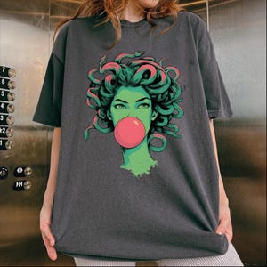 May include: A white ceramic mug with a black handle and the text "But first, coffee" in a black, handwritten-style font. The mug is on a white surface.