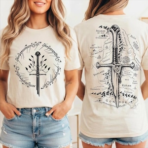 May include: Beige t-shirt featuring a black sword and tree design within a circular frame on the front. The back of the shirt displays a map with a sword illustration and the word "GONDOR". The shirt is a short-sleeved, casual wear item.
