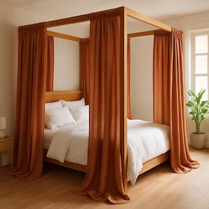 Puede incluir: Una cama con dosel de madera con cortinas de color óxido. La cama tiene un marco de madera clara y ropa de cama y almohadas blancas. Una pequeña mesita de noche con una lámpara es visible a la izquierda.