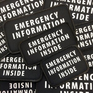 Puede incluir: Primer plano de varios parches de tela negra con texto blanco que dice "Emergency Information Inside".