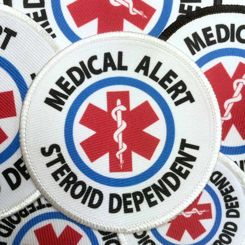 Puede incluir: Parche redondo blanco con un s&iacute;mbolo de estrella de la vida roja con una serpiente y un bast&oacute;n en su interior. El texto alrededor de la estrella dice "MEDICAL ALERT STEROID DEPENDENT".