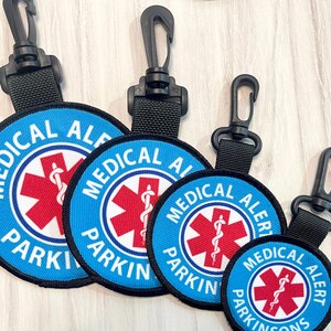 May include: Four blue and red medical alert keychains with black lanyards. The keychains have the text "Medical Alert Parking" and a red medical symbol.